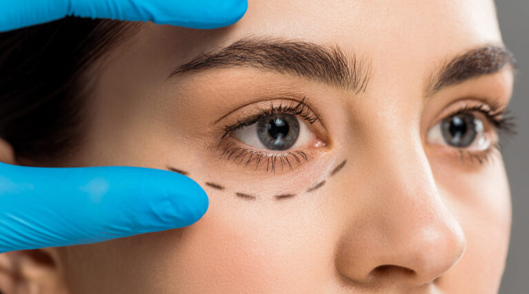 cropped view of plastic surgeon in latex glove touching face of woman isolated on grey cropped view of plastic surgeon in latex glove touching face of woman isolated on grey