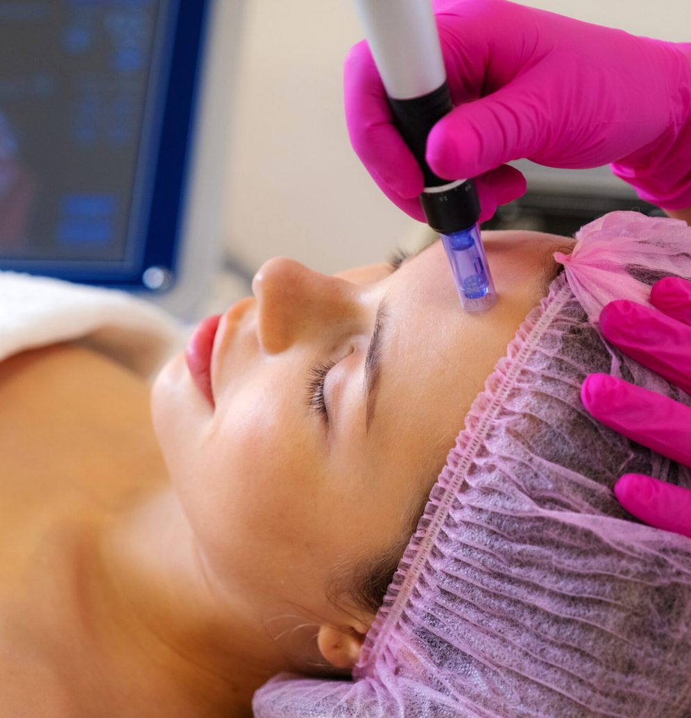 Beautician makes skin care procedure on a  face. Woman in a spa salon on cosmetic procedures for facial care. Cosmetologist making a woman a therapeutic laser processing on a face.