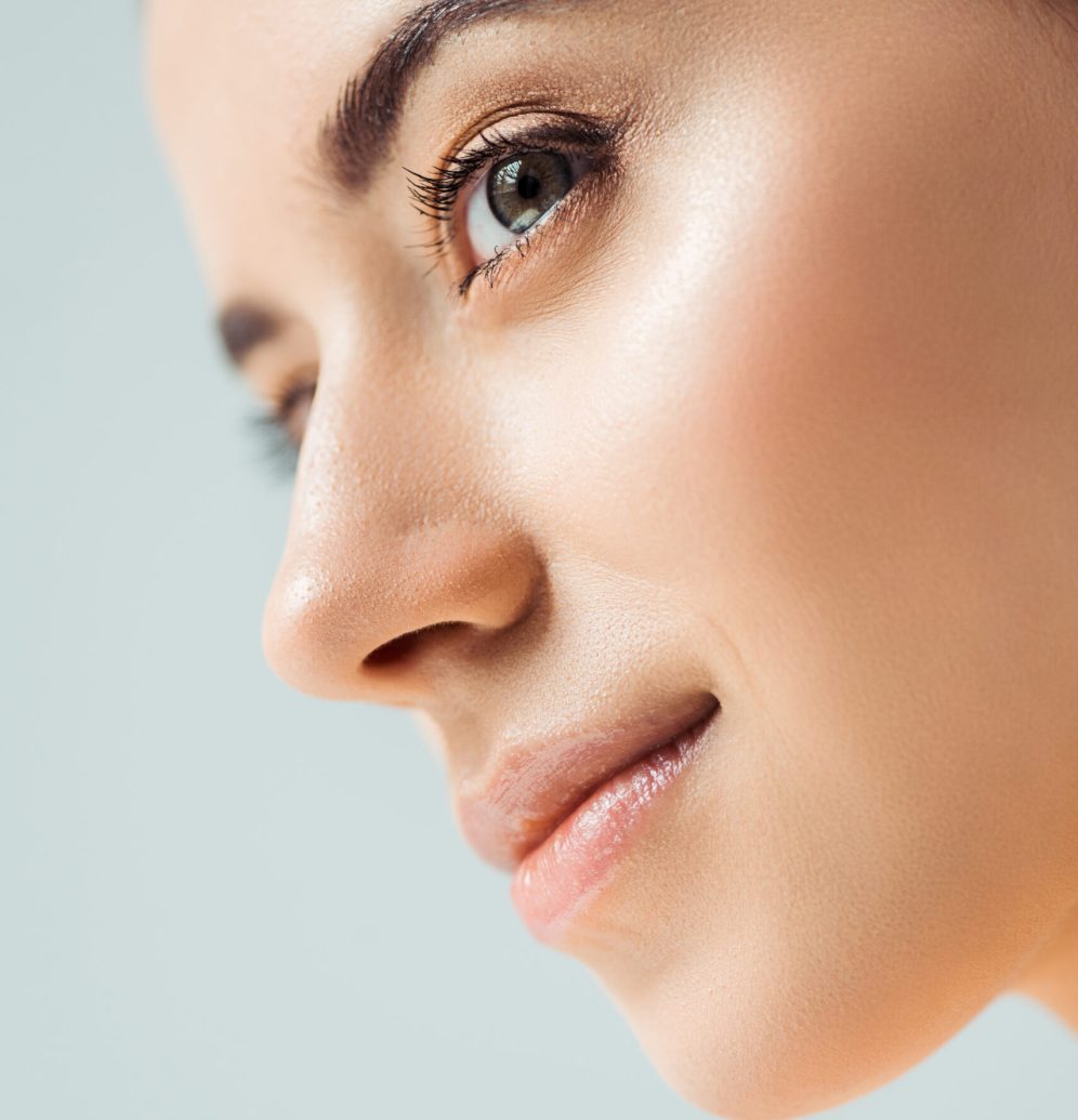 close up of young smiling woman with shiny lips and golden eye shadow isolated on grey
