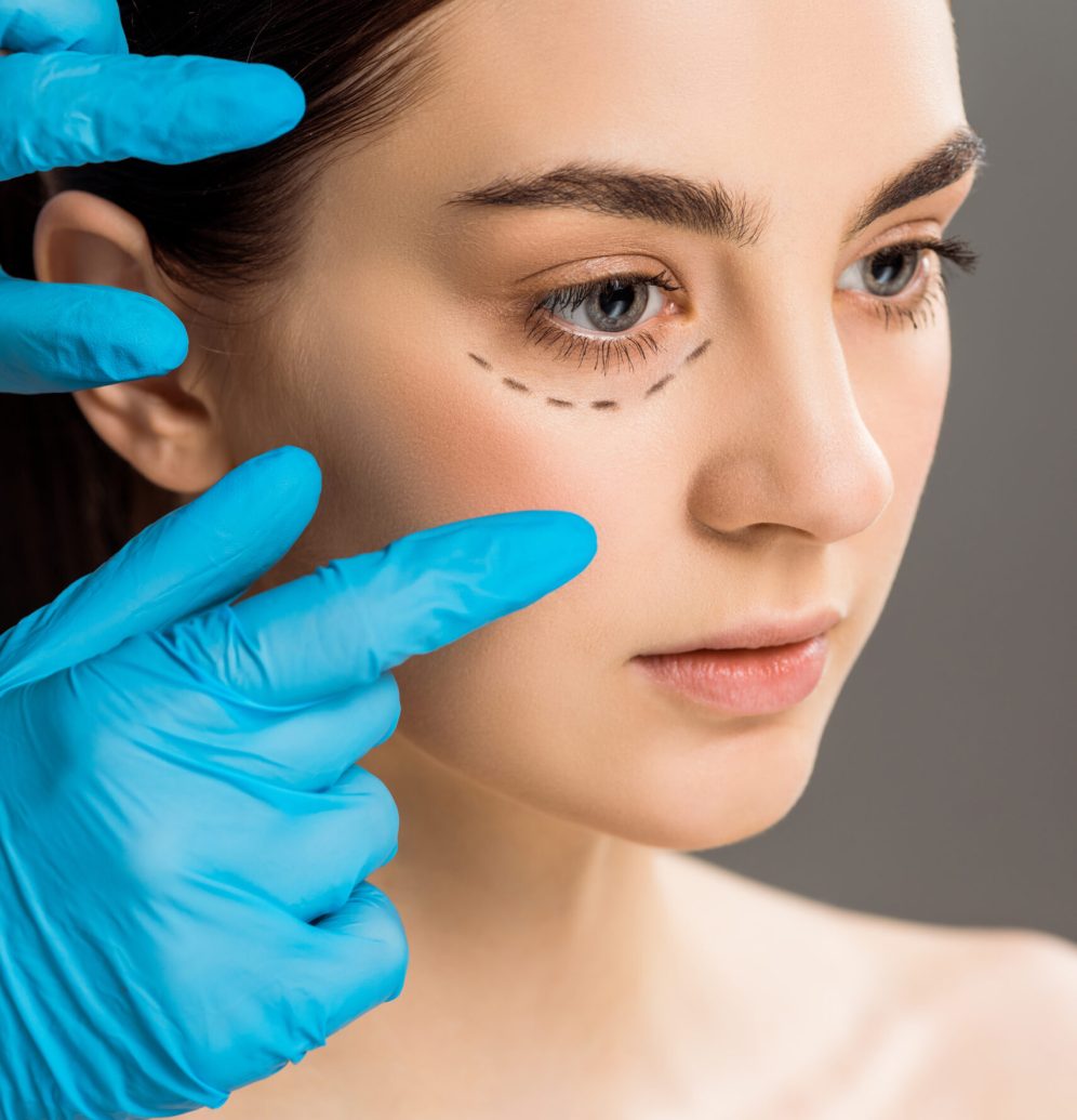 cropped view of plastic surgeon in latex gloves near woman with marks on face isolated on grey