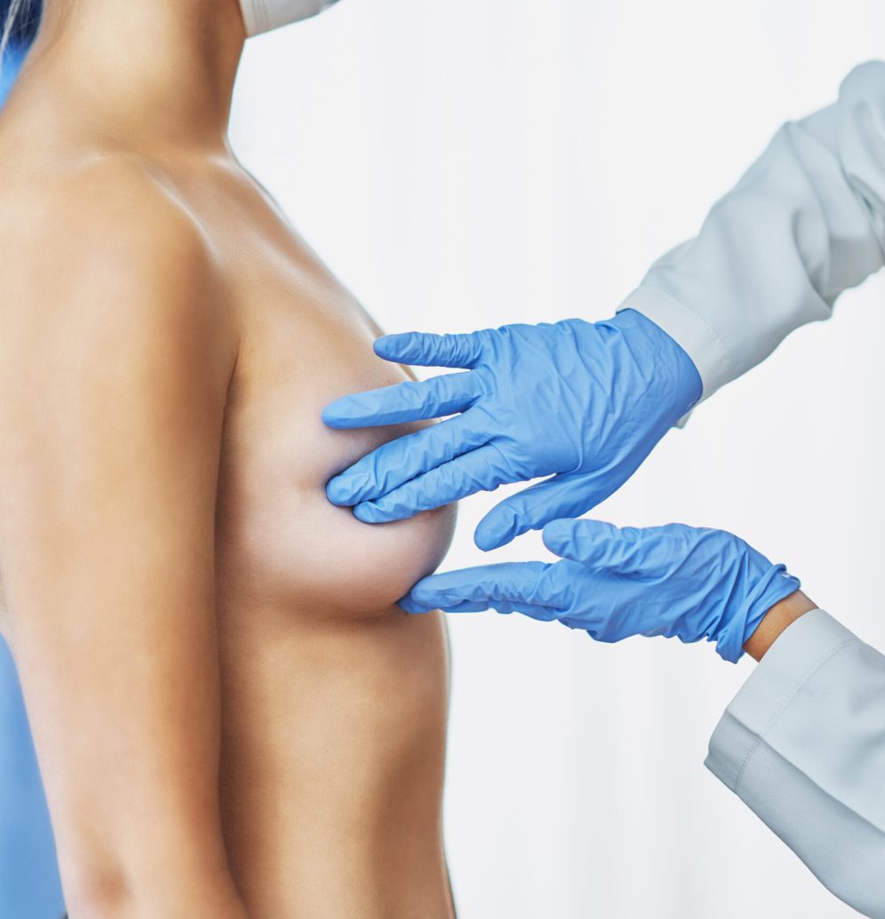 Picture of doctor in mask checking up breast to her patient