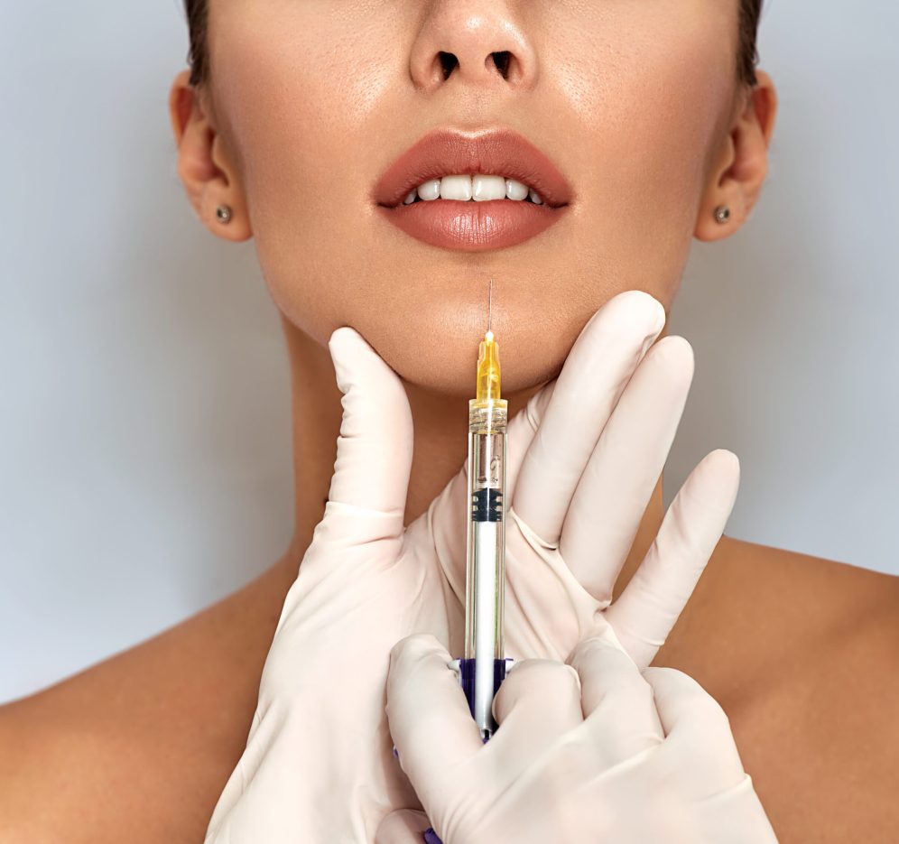 Syringe near womans mouth, injections for increase lips shape. Cropped sensual female lips, procedure lip augmentation